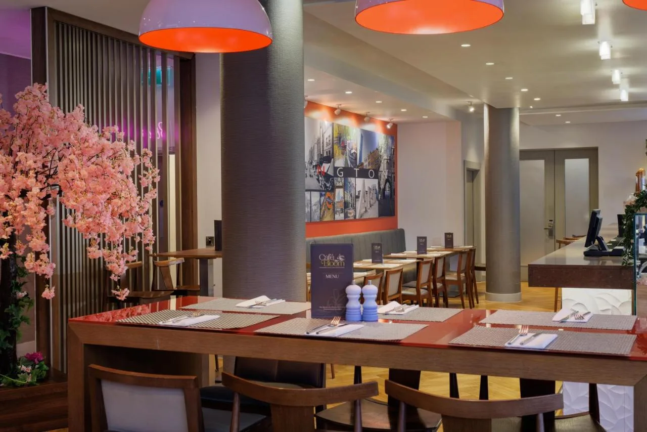 a restaurant with tables and chairs and pink flowers at DoubleTree by Hilton London Angel Kings Cross in London